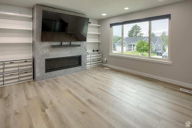 unfurnished living room with baseboards, wood finished floors, recessed lighting, and a fireplace