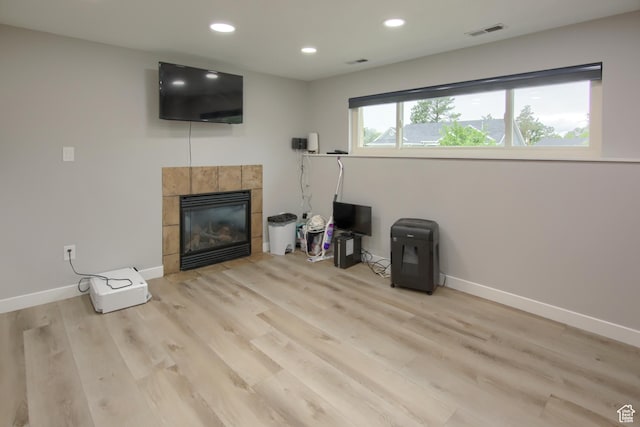 living area featuring a tiled fireplace, light wood-style flooring, baseboards, and recessed lighting