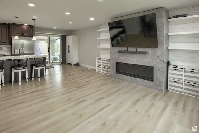 living area featuring recessed lighting, light wood-type flooring, a high end fireplace, and baseboards