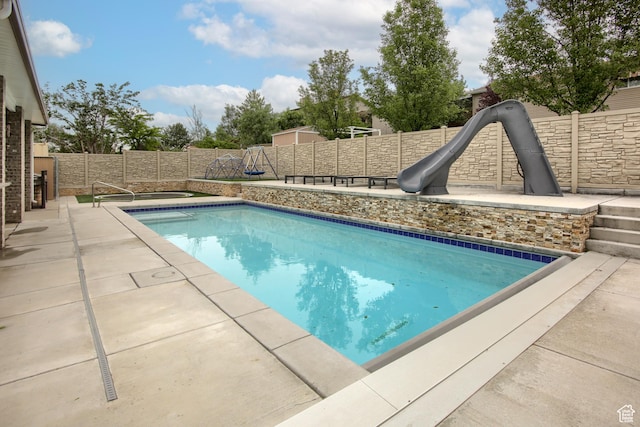 view of pool featuring a fenced backyard, a water slide, and a patio area