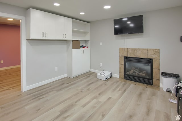 unfurnished living room with light wood-style flooring, a fireplace, baseboards, and recessed lighting