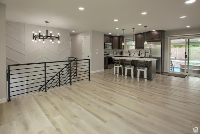 dining space featuring light wood finished floors, a chandelier, baseboards, and recessed lighting
