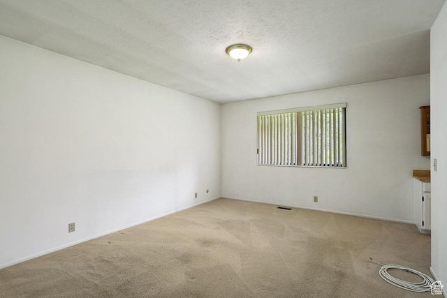 carpeted spare room with baseboards and a textured ceiling