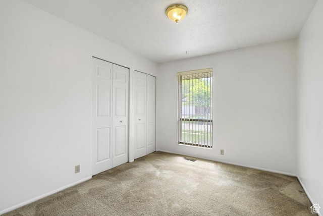 unfurnished bedroom with carpet, multiple closets, and baseboards