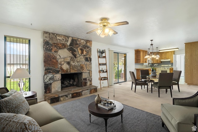 living room with light colored carpet, a ceiling fan, a chandelier, and a fireplace
