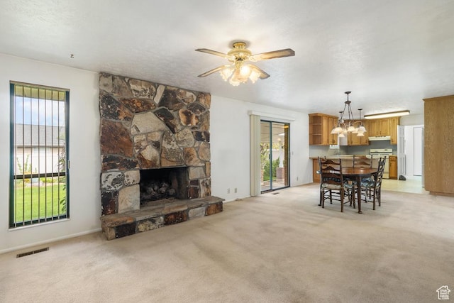 living room with a chandelier, ceiling fan, light carpet, a fireplace, and a textured ceiling