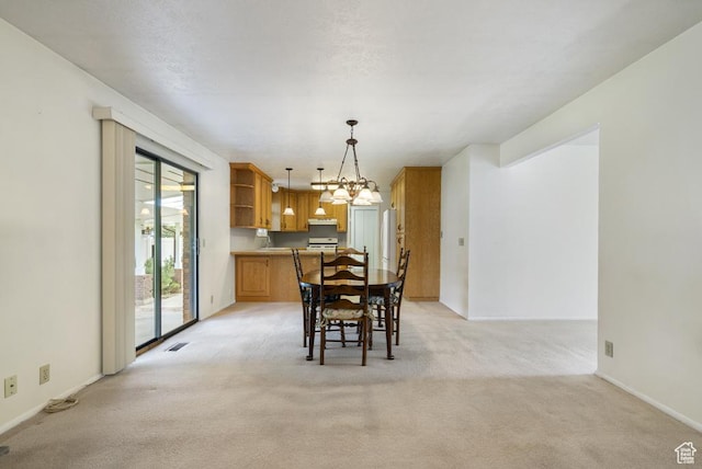 dining space featuring light carpet, a chandelier, and baseboards