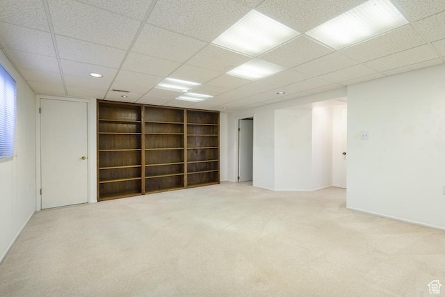 carpeted spare room with built in shelves, a paneled ceiling, and baseboards