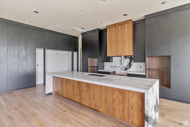 6078 S Heughs Canyon Way, Holladay, UT 84121 - kitchen with light wood-type flooring, modern cabinets, a large island, decorative backsplash, and light stone counters