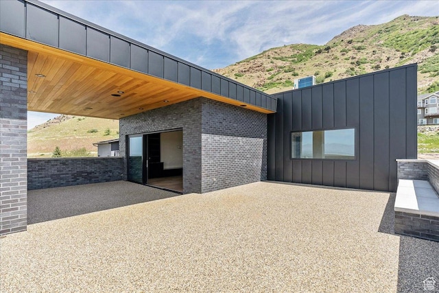 6078 S Heughs Canyon Way, Holladay, UT 84121 - view of side of home with board and batten siding, a mountain view, and brick siding