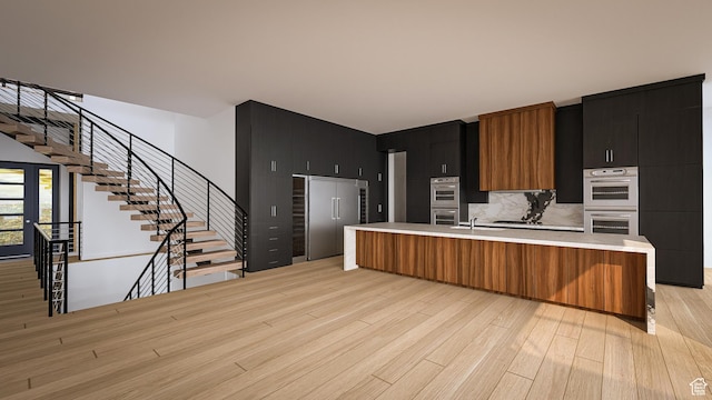 6078 S Heughs Canyon Way, Holladay, UT 84121 - kitchen with light countertops, light wood-type flooring, stainless steel appliances, a large island with sink, and dark cabinetry