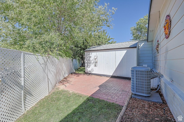 view of yard with central AC, fence, a patio, a storage shed, and an outbuilding