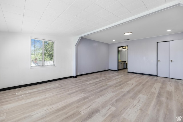 unfurnished room with wood finished floors, baseboards, recessed lighting, and arched walkways