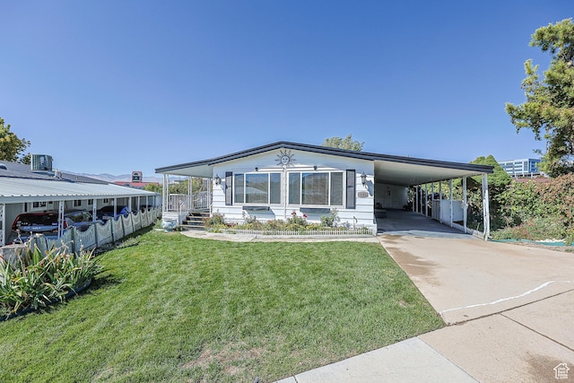 manufactured / mobile home with concrete driveway, a front yard, a carport, and covered porch