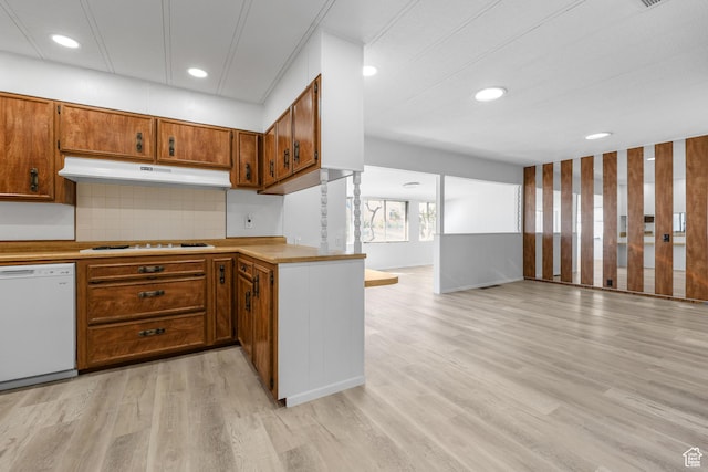 kitchen featuring white appliances, under cabinet range hood, open floor plan, brown cabinets, and light wood-style floors
