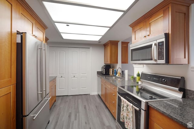 48 W Broadway Unit 1804N, Salt Lake City, UT 84101 - kitchen featuring appliances with stainless steel finishes, a sink, light wood-type flooring, brown cabinetry, and dark stone countertops