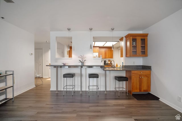 48 W Broadway Unit 1804N, Salt Lake City, UT 84101 - kitchen featuring brown cabinets, glass insert cabinets, dark wood-type flooring, a breakfast bar, and a peninsula