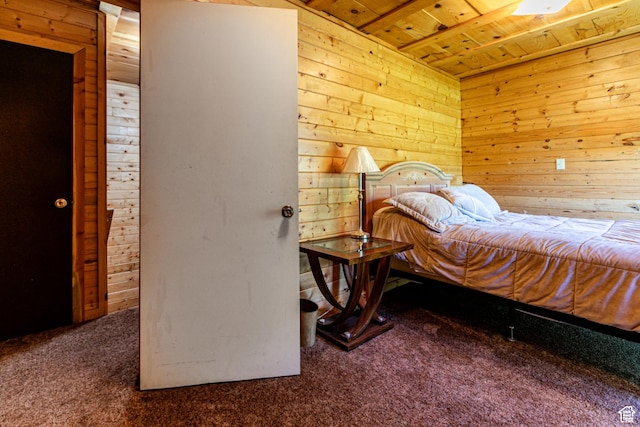 carpeted bedroom with wooden ceiling and wood walls