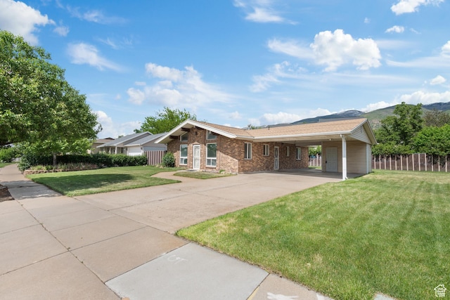 single story home featuring concrete driveway, an attached carport, a mountain view, and brick siding