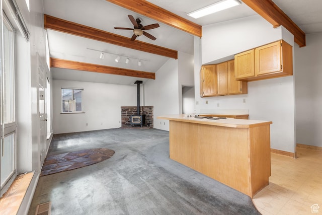 kitchen featuring a wood stove, beam ceiling, a ceiling fan, white electric cooktop, and open floor plan