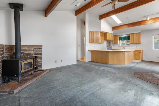 kitchen featuring a wood stove, light carpet, a peninsula, and open floor plan