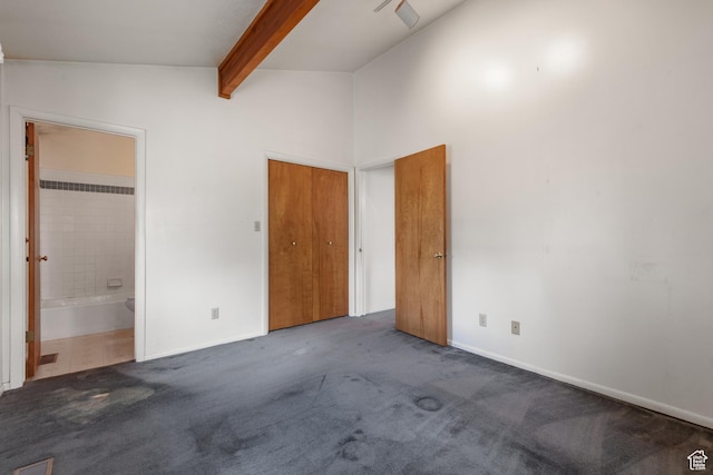 unfurnished bedroom with beamed ceiling, carpet floors, baseboards, ensuite bath, and high vaulted ceiling