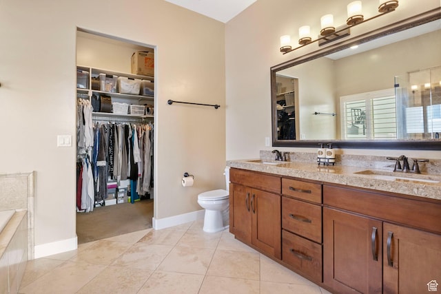 bathroom featuring a spacious closet, toilet, double vanity, baseboards, and a relaxing tiled tub