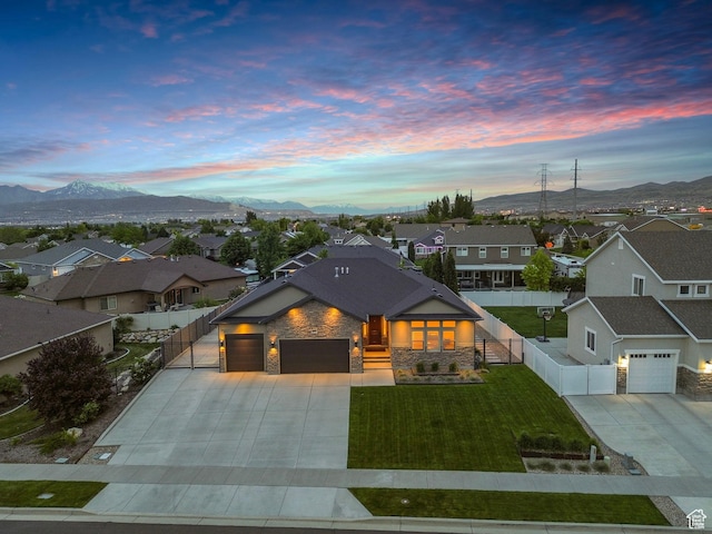 contemporary house with concrete driveway, stone siding, a residential view, a garage, and a gate