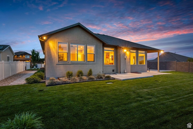 back of property at dusk with stucco siding and a patio