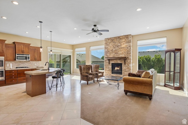 living area featuring recessed lighting, ceiling fan, a stone fireplace, and light tile patterned floors
