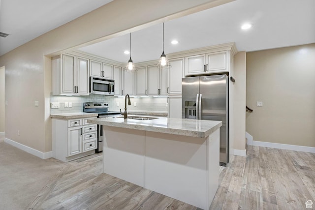 kitchen featuring stainless steel appliances, a sink, tasteful backsplash, baseboards, and light wood finished floors