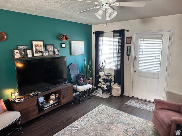 living area featuring wood finished floors, a ceiling fan, baseboards, and a textured ceiling