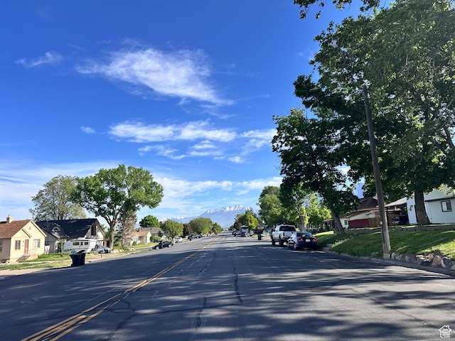 view of asphalt road with a residential view, curbs, and sidewalks