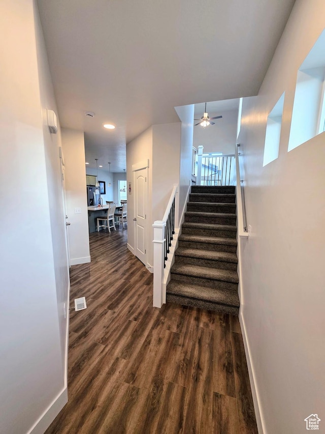 stairs featuring a ceiling fan, baseboards, wood finished floors, and recessed lighting