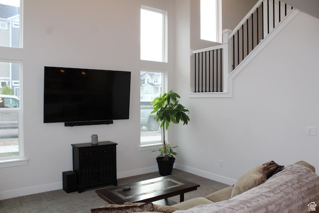 carpeted living area with baseboards, a high ceiling, and stairway