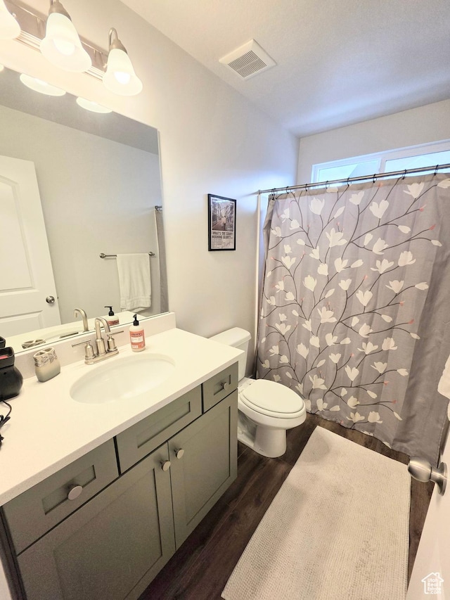 bathroom featuring wood finished floors, vanity, toilet, and curtained shower