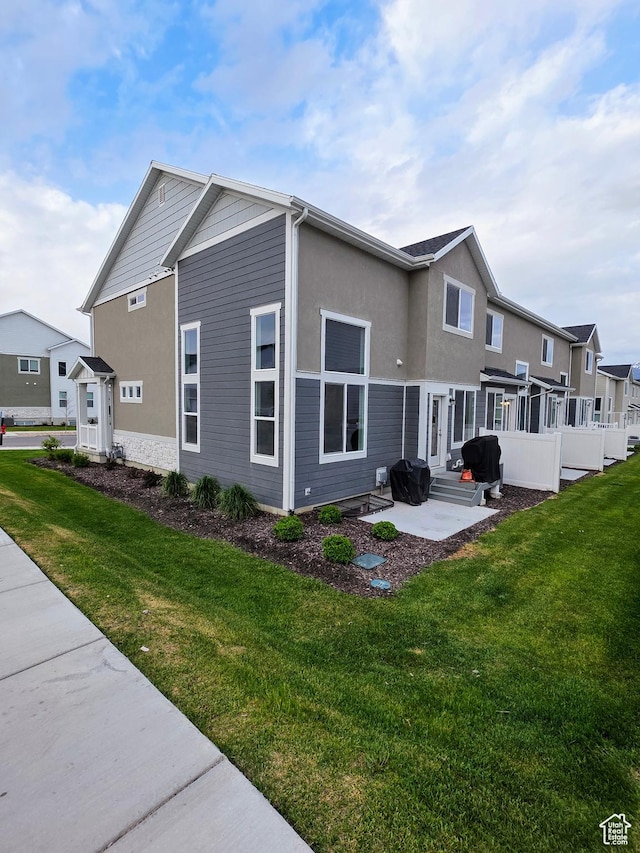 rear view of house featuring a patio, a lawn, stucco siding, and entry steps