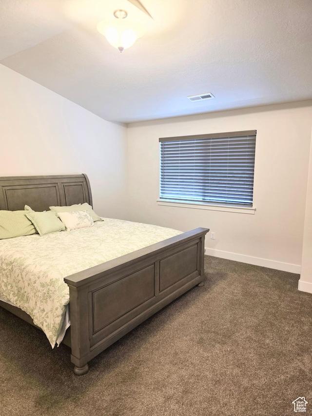 bedroom with dark colored carpet and baseboards