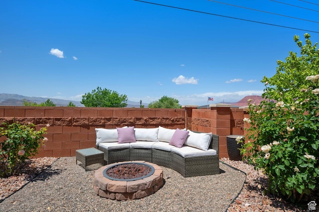 view of patio / terrace featuring fence, an outdoor fire pit, and a mountain view