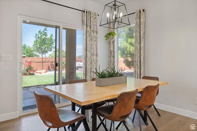 dining area with baseboards, a chandelier, healthy amount of natural light, and light wood-style flooring