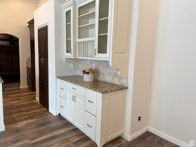 bar area featuring dark wood finished floors, baseboards, and decorative backsplash