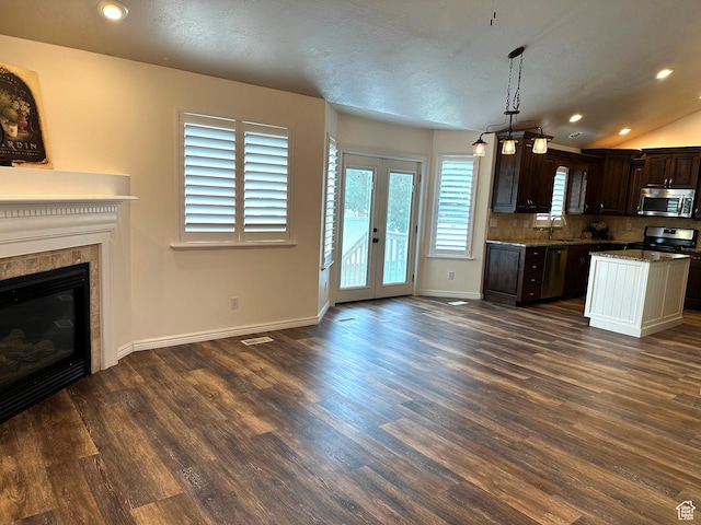 kitchen with stainless steel appliances, a sink, dark brown cabinets, dark wood-style floors, and a fireplace