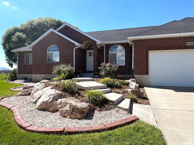 ranch-style house featuring brick siding, an attached garage, roof with shingles, and concrete driveway