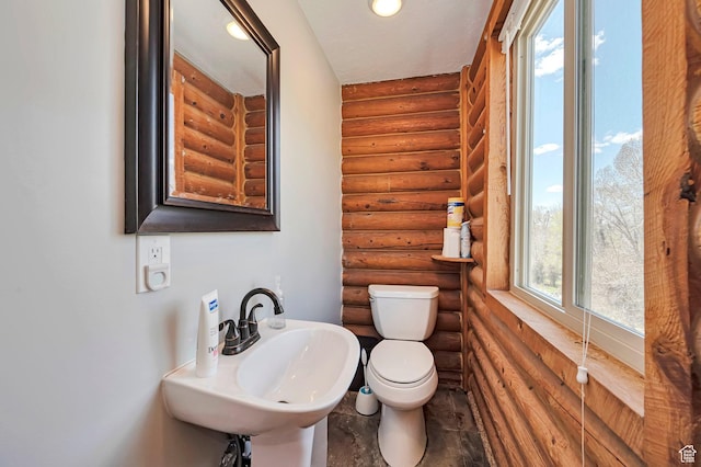 half bath with log walls, a sink, and toilet