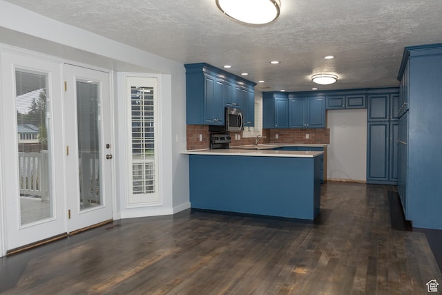 135 N 3rd E, Preston, ID 83263 - kitchen featuring appliances with stainless steel finishes, blue cabinets, a peninsula, dark wood-style floors, and a sink