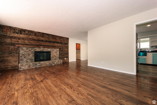 4872 S Burch Creek Dr, South Ogden, UT 84403 - unfurnished living room with dark wood-type flooring, a stone fireplace, and baseboards
