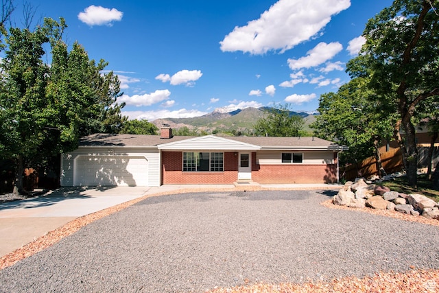4872 S Burch Creek Dr, South Ogden, UT 84403 - ranch-style house featuring brick siding, an attached garage, a mountain view, concrete driveway, and a chimney