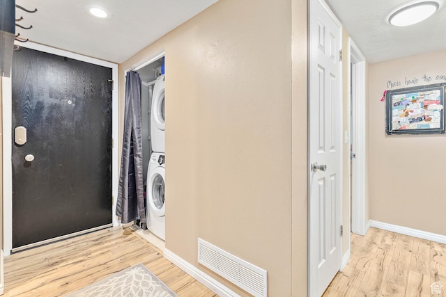 washroom featuring estacked washer and dryer, wood finished floors, and baseboards