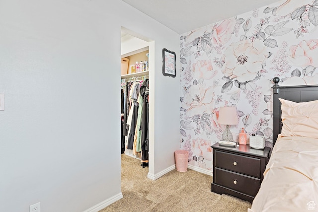 bedroom featuring a spacious closet, light colored carpet, baseboards, and a closet