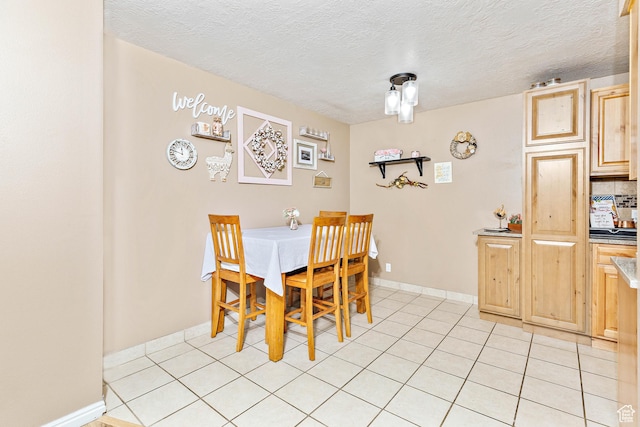 dining area featuring a textured ceiling, light tile patterned floors, and baseboards